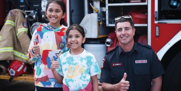 A Fire and Rescue worker posing for a photo with two kids